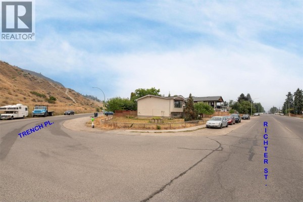 Street view showing the intersection of Richter Street and Trench Place with houses and cars. - 651 Richter Street, Kelowna