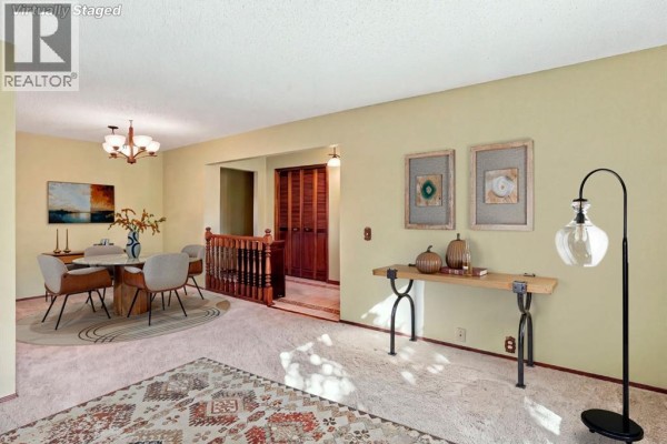 Dining area with a round table and chairs, connected to a hallway with wood paneling. - 652 Oakwood Place Sw, Calgary