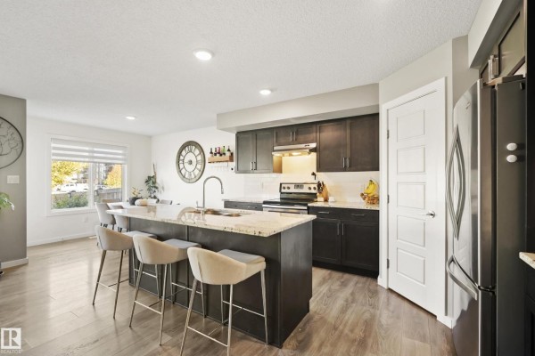 Kitchen and dining area with a large island, granite countertops, dark cabinets, and stainless steel appliances. - 6520 59 Av, Beaumont