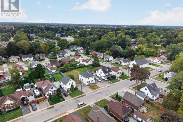 Aerial view of a white two-story house with a dark roof, driveway, and surrounding properties. - 6520 Barker Street, Niagara Falls