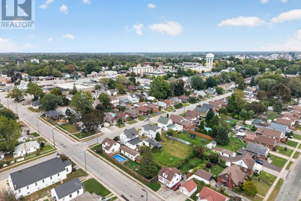 Aerial view of a residential neighborhood with houses, trees, and streets under a partly cloudy sky. - 6520 Barker Street, Niagara Falls