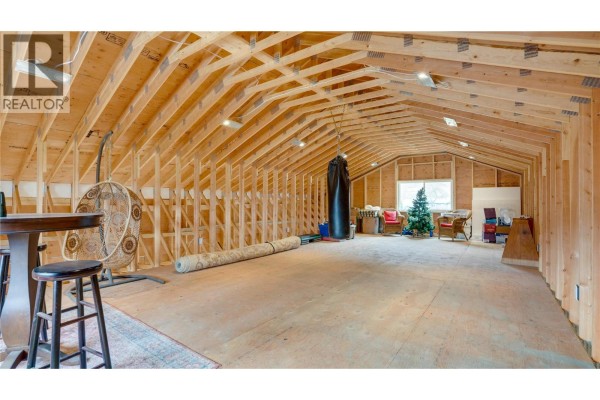 Large unfinished attic space with exposed wooden beams, a punching bag, and furniture. - 6524 Highway 6, Coldstream
