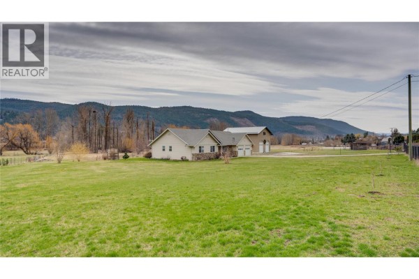 Aerial view of a beige house with a three-car garage and a large workshop. - 6524 Highway 6, Coldstream