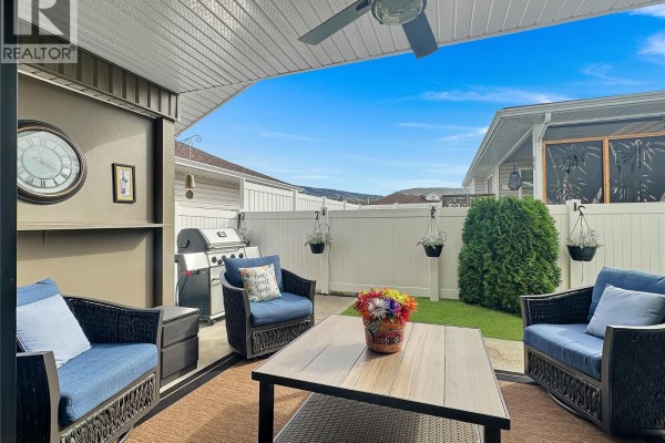 Covered patio with wicker furniture, a gas grill, and a view of a fenced backyard and distant hills. - 6526 Tucelnuit Drive Unit# 40, Oliver