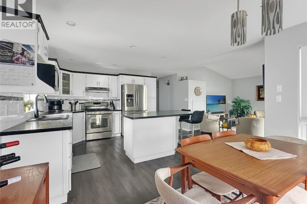 Bright kitchen with white cabinets, stainless steel appliances, and a breakfast bar overlooking a dining area and living room. - 6526 Tucelnuit Drive Unit# 40, Oliver
