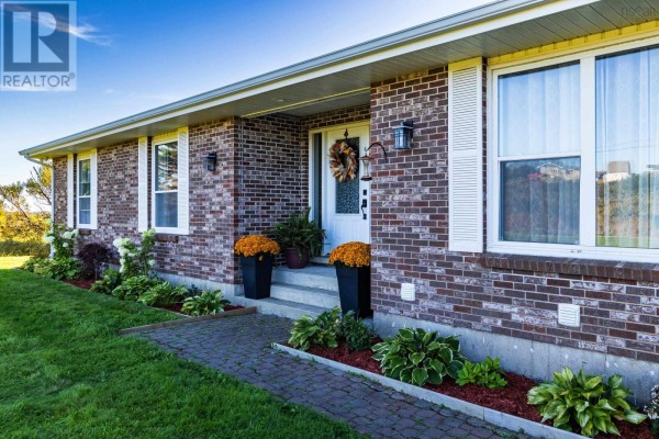 Close-up of the front entrance of the brick bungalow with landscaping. - 653 Ross Durkee Road, Sandford