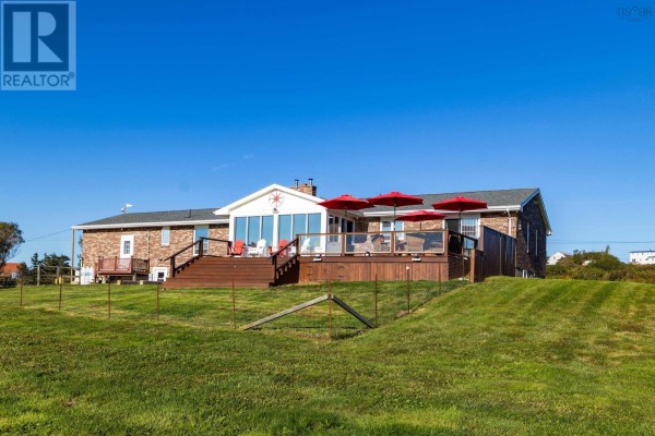 Rear exterior view of the bungalow with a large wooden deck and red umbrellas. - 653 Ross Durkee Road, Sandford
