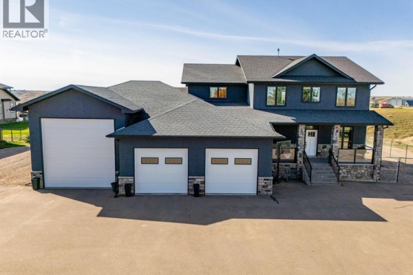 Front exterior of a dark blue two-story house with a triple garage and stone accents. - 6531b Township Road 132, Rural Cypress County