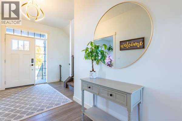 Entryway with white front door, grey console table, and large round mirror. - 6531b Township Road 132, Rural Cypress County