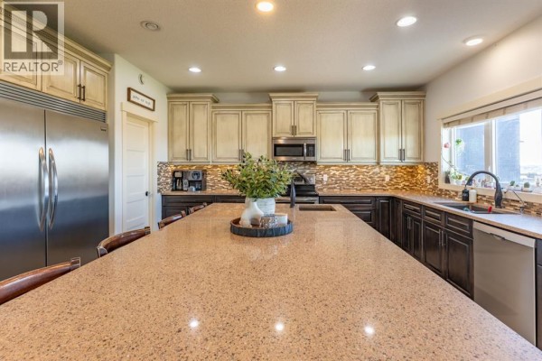 Large kitchen island with granite countertop and cream-colored cabinets with dark island cabinets. - 6531b Township Road 132, Rural Cypress County