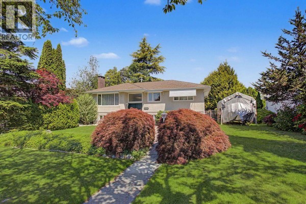 View of the house from the street with a paved walkway, green lawn, and mature trees. - 6541 Grant Street, Burnaby