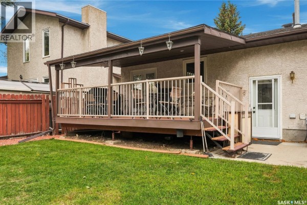 Close-up of a covered wooden deck with outdoor seating and stairs leading to the yard. - 6546 Rush Place, Regina