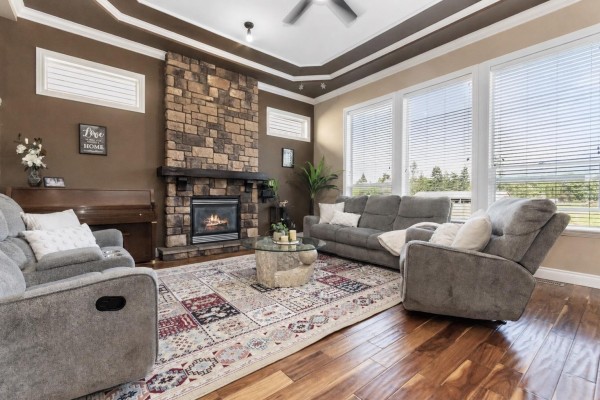 Cozy bedroom with dark furniture, tree-patterned bedding, and wall-mounted TV - 6556 Lavender Place, Sardis South, Chilliwack