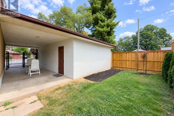 Carport area with outdoor seating, adjacent storage shed, and wooden fence backyard. - 6558 O'neil Street, Niagara Falls