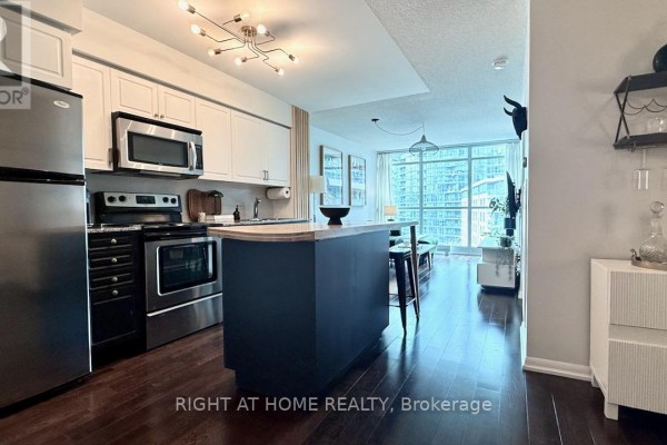 Kitchen with stainless steel appliances, dark blue island with wood countertop, and city view. - 656 - 209 Fort York Boulevard S, Toronto