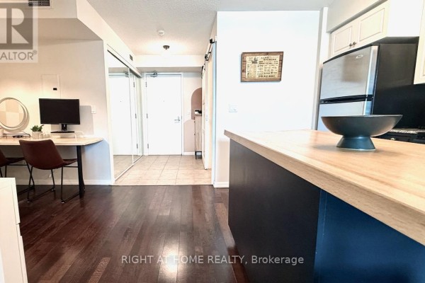 Corner of a kitchen with a blue island and entryway with mirrored closet doors. - 656 - 209 Fort York Boulevard S, Toronto