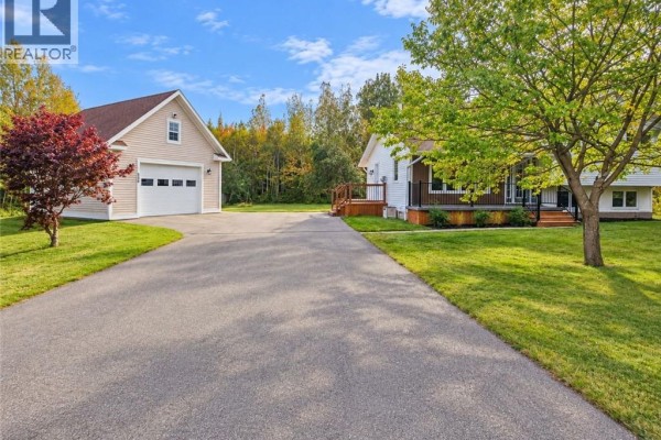 View of white house and detached garage with driveway and green lawn. - 656 Sureau Blanc, Tracadie