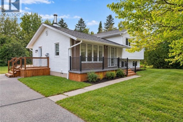Front of white house with dark railing porch and wooden deck. - 656 Sureau Blanc, Tracadie