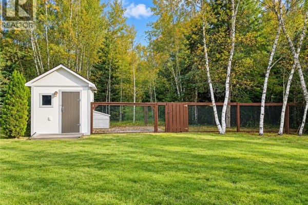 White shed and fenced-in area with chicken coop in grassy yard. - 656 Sureau Blanc, Tracadie
