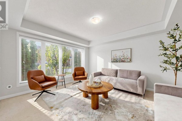 Living room with a large window, light gray walls, and neutral furniture. - 657 Cargill Path, Milton