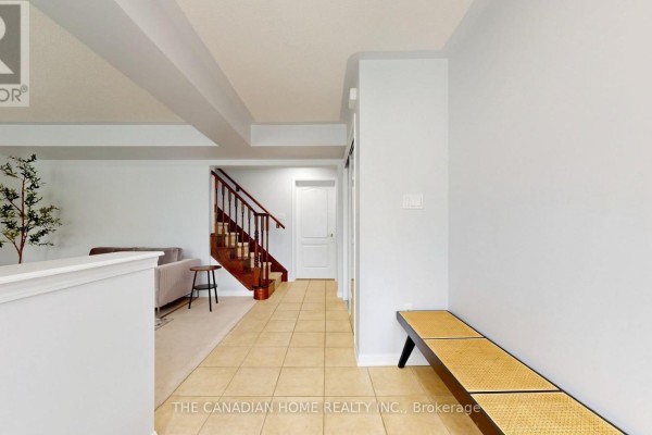 Hallway with beige tile flooring, leading to a staircase and interior doors. - 657 Cargill Path, Milton