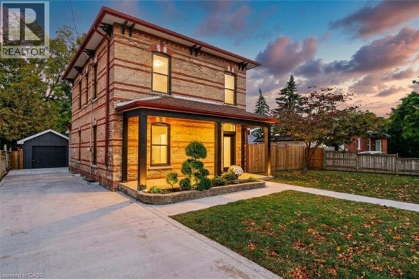 Front exterior of a two-story brick house with a covered porch and manicured lawn. - 657 Frances Street, Woodstock