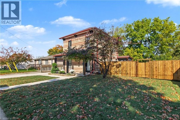 Front exterior of a brick house with a porch, green lawn, and mature trees. - 657 Frances Street, Woodstock