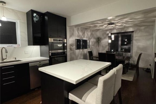Open concept kitchen and dining area. Kitchen features black cabinets, a white island, and stainless steel appliances. - 657 Jupiter Court, Sudbury