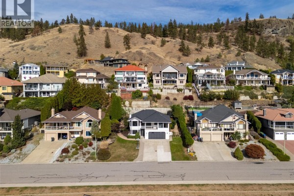 Street view of houses on a hillside, featuring 657 Royal View Drive in the center. - 657 Royal View Drive, Kelowna