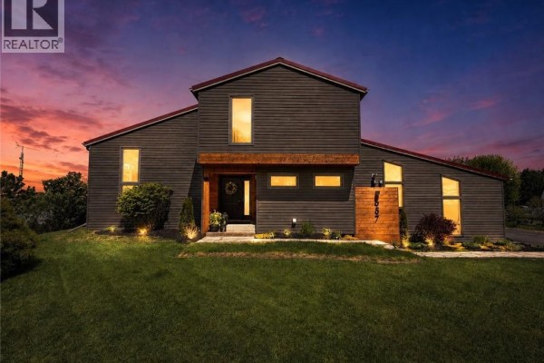 Contemporary house exterior with dark siding, wood accents, and green lawn. - 657 Windham Road 14, Simcoe