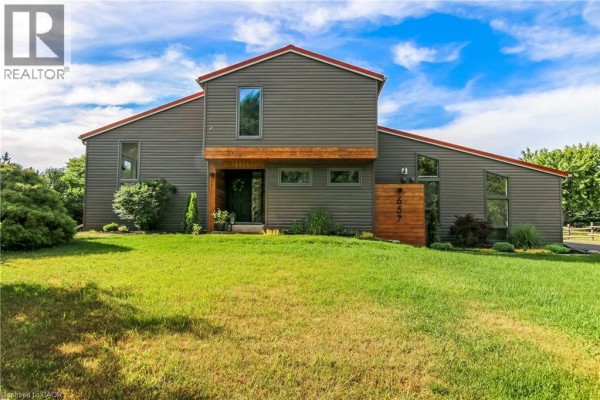 Attached two-car garage with dark siding and a green garage door. - 657 Windham Road 14, Simcoe