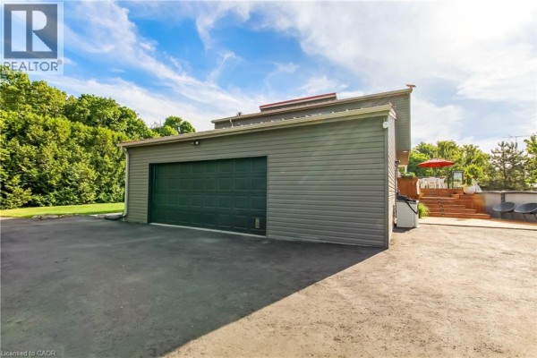 Detached two-bay garage with dark wood siding and a covered porch. - 657 Windham Road 14, Simcoe