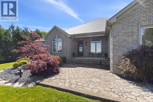 Sunroom with brick wall, wicker furniture, blue cushions, and large windows overlooking water. - 6576 Talbot Trail, Merlin