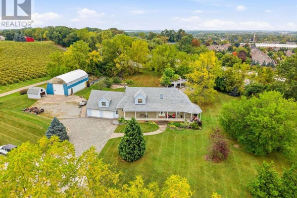 Aerial view of a residential property featuring a house, barn, and surrounding trees. - 6585 Steele Street, Niagara On The Lake