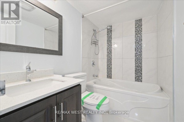 Bathroom with a bathtub, modern vanity, and tiled walls featuring decorative accents - 66 - 1624 Bloor Street E, Mississauga
