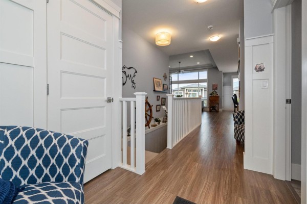 Interior hallway with wood flooring, white trim, white doors, and a view of stairs. - 66 46213 Hakweles Road, Sardis East Vedder, Chilliwack