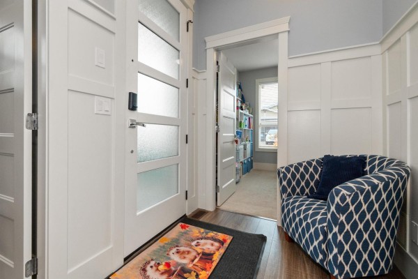 Front entrance with a frosted glass door, white trim, a patterned armchair, and an open doorway to a room. - 66 46213 Hakweles Road, Sardis East Vedder, Chilliwack