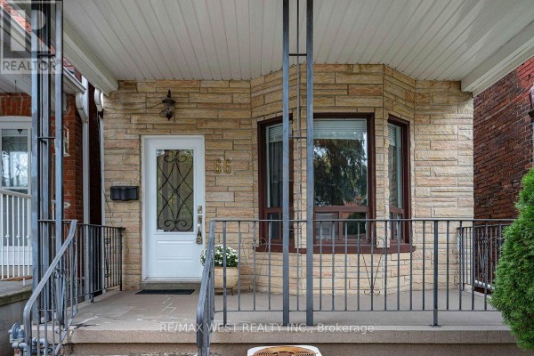 Covered front porch with stone facade, bay window, and white door numbered 66. - 66 Bristol Avenue, Toronto