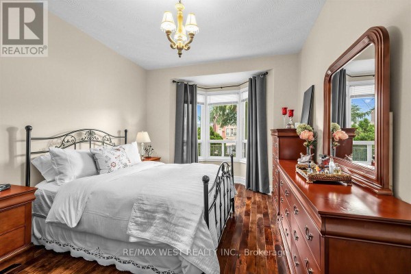 Bedroom with a queen-size bed, dark wood floors, and a bay window view. - 66 Bristol Avenue, Toronto