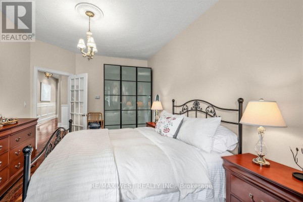 Bedroom with a queen-size bed, dark wood floors, and double doors leading to another room. - 66 Bristol Avenue, Toronto