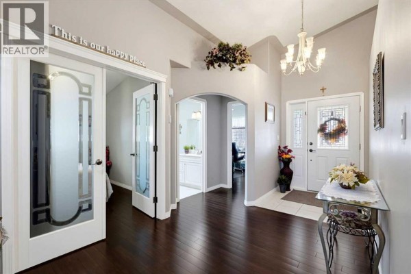 Foyer with dark wood floors, white doors, and an arched doorway to a bathroom. - 66 Dumas Crescent, Red Deer