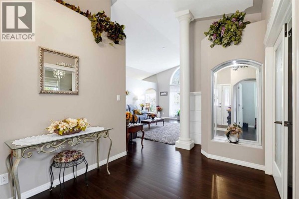 Interior foyer with dark wood floors, a decorative console table, and a large arched mirror. - 66 Dumas Crescent, Red Deer