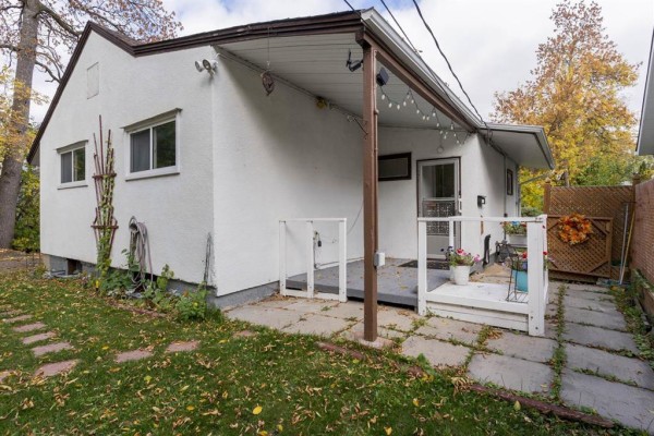 Rear exterior of a bungalow with a white siding back wall, concrete patio, and decorative fencing. - 66 Essar Avenue, Winnipeg