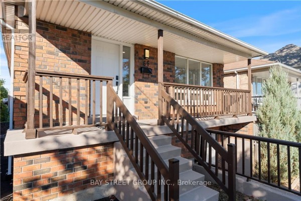 Close-up view of the front entrance of a brick house, showing a white door and wooden porch railings. - 66 Ewen Road, Hamilton