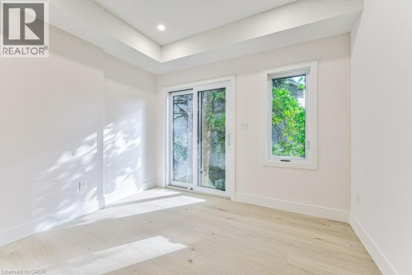 Bright room with a sliding glass door leading outdoors and a large window with greenery outside. - 66 Gage Avenue Unit# 1, Kitchener