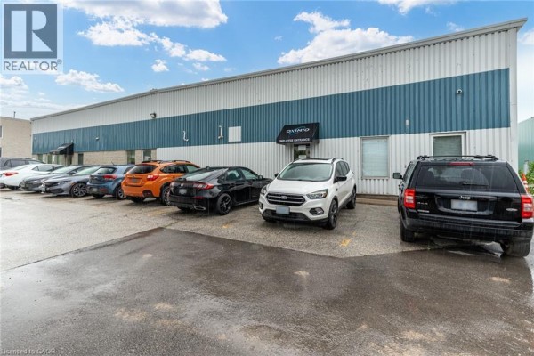 Parking lot in front of a commercial building entrance with several cars parked and a sign for "EMPLOYEE ENTRANCE". - 66 Innovation Drive, Dundas
