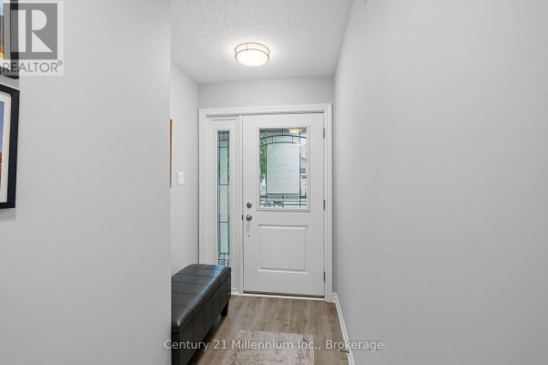 Foyer with light gray walls, a white double door, a decorative glass sidelight, and a dark bench. - 66 Ivy Crescent, Wasaga Beach