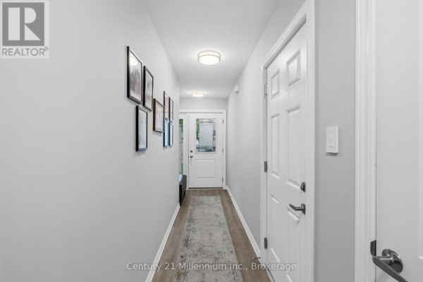 Hallway with light gray walls, framed pictures on the left, and white doors on the right. - 66 Ivy Crescent, Wasaga Beach