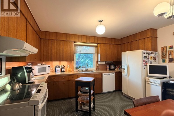 Kitchen with wood cabinetry, stainless steel appliances, and a counter with a sink. - 66 Kasper Crescent, Assiniboia