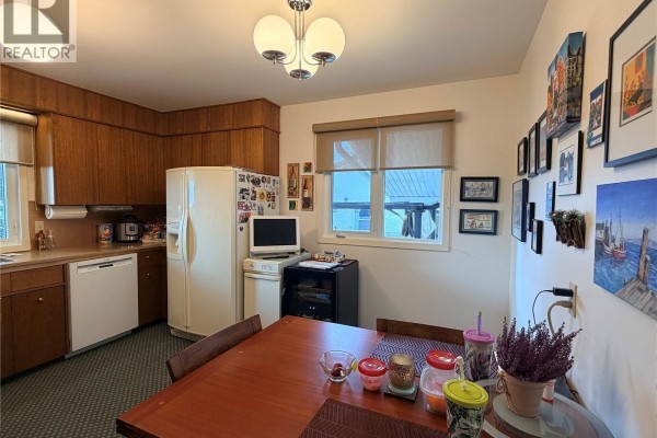 Dining area in the kitchen with a wooden table, chairs, and a window view. - 66 Kasper Crescent, Assiniboia